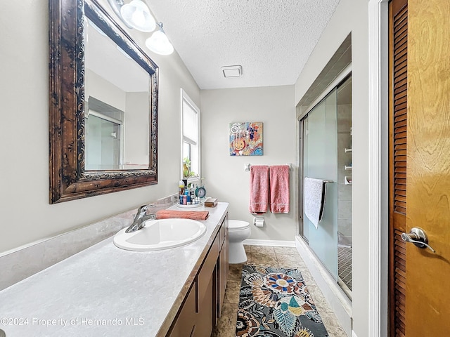 bathroom featuring vanity, tile patterned flooring, toilet, a textured ceiling, and a shower with shower door