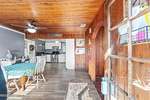 dining room featuring wood walls, ceiling fan, dark wood-type flooring, and wooden ceiling