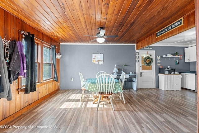 unfurnished dining area with wood walls, light hardwood / wood-style flooring, ceiling fan, and wooden ceiling