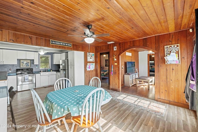 dining area with sink, wooden walls, ceiling fan, light wood-type flooring, and wood ceiling