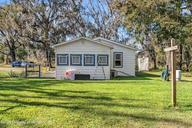 back of property featuring central air condition unit and a yard