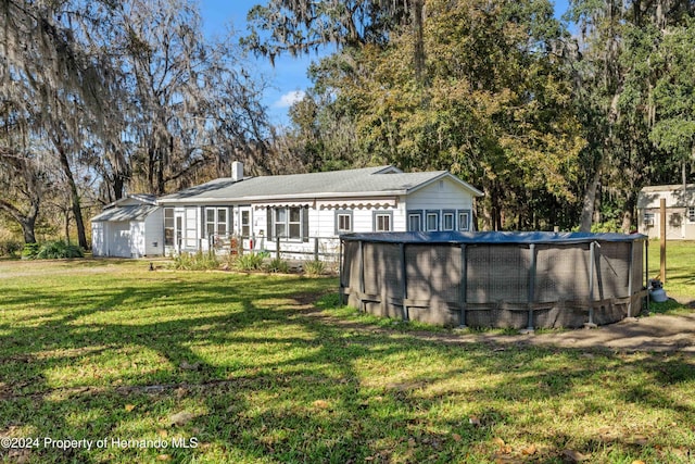 back of property with a lawn and a covered pool