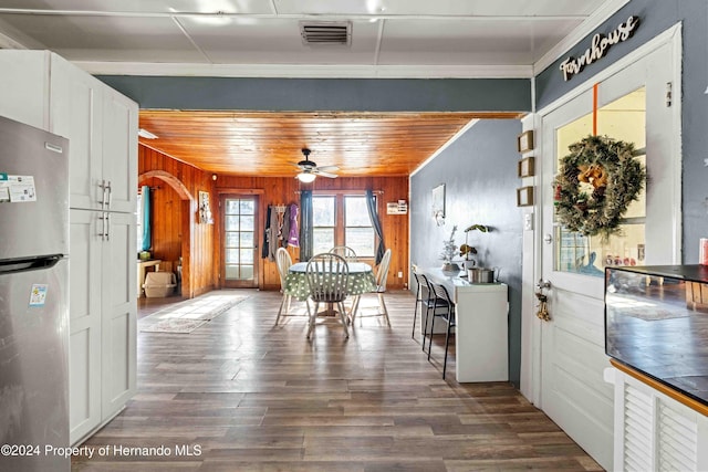 dining space with wooden ceiling, crown molding, wooden walls, ceiling fan, and dark hardwood / wood-style flooring