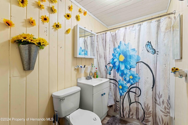 bathroom with a shower with curtain, vanity, toilet, and wood walls