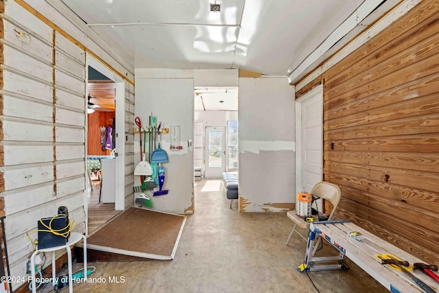 miscellaneous room with a workshop area, ceiling fan, concrete floors, lofted ceiling, and wood walls