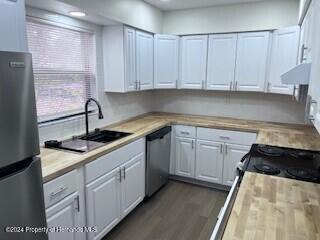 kitchen featuring dark wood-type flooring, white cabinets, sink, stainless steel appliances, and extractor fan