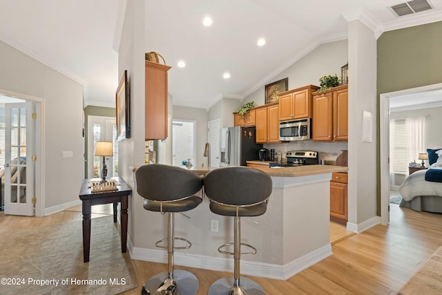 kitchen with a breakfast bar area, light hardwood / wood-style floors, ornamental molding, and appliances with stainless steel finishes