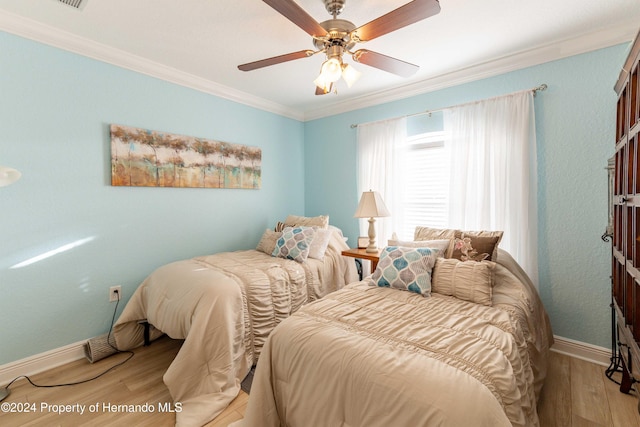 bedroom featuring ceiling fan, light wood-type flooring, and crown molding