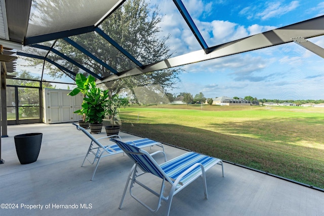 view of patio / terrace featuring glass enclosure and a storage shed