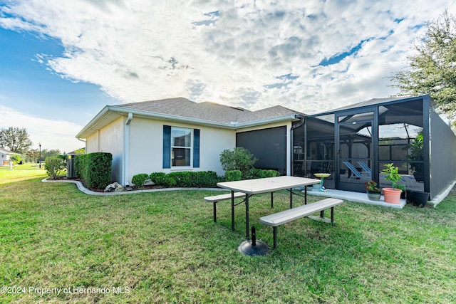 back of property featuring glass enclosure and a lawn