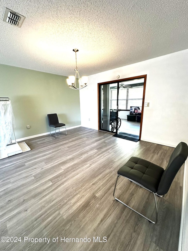 sitting room with an inviting chandelier, hardwood / wood-style floors, and a textured ceiling