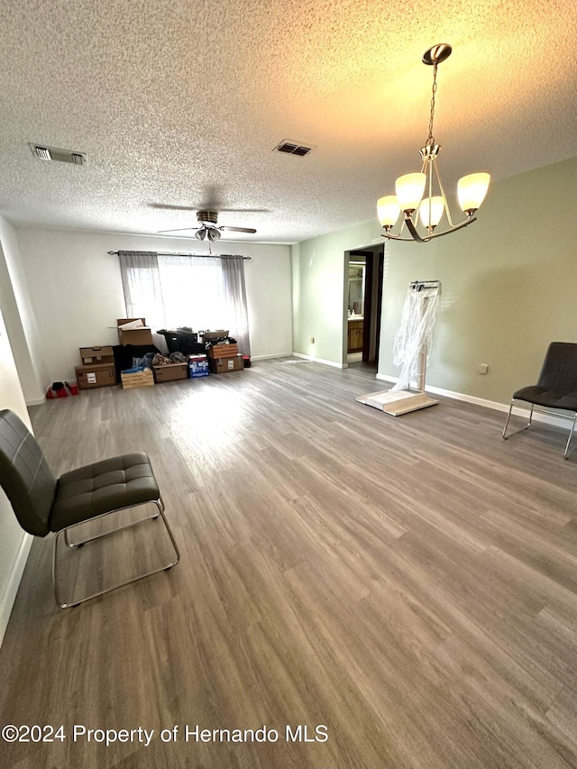 living room with hardwood / wood-style floors, ceiling fan with notable chandelier, and a textured ceiling