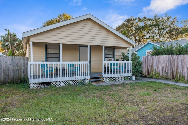 bungalow-style home with covered porch and a front lawn