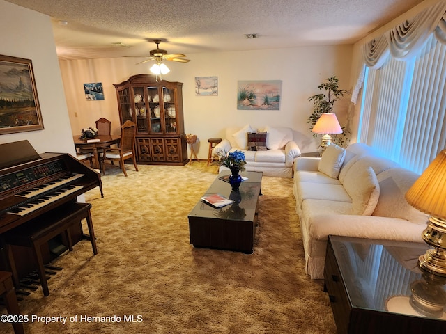 living room featuring ceiling fan, a textured ceiling, and carpet