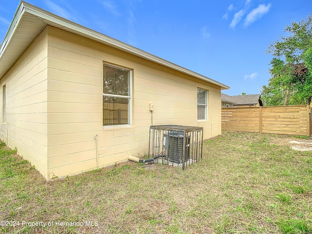 view of side of property with a lawn and cooling unit