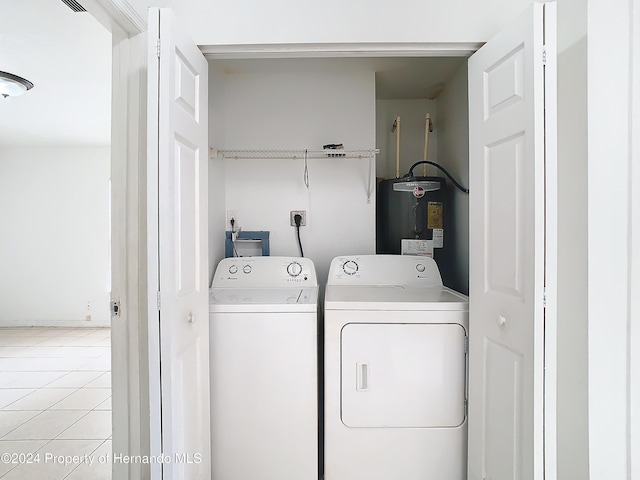 clothes washing area with water heater, light tile patterned flooring, and independent washer and dryer