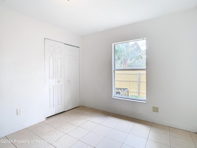 unfurnished bedroom with a closet, light tile patterned flooring, and multiple windows