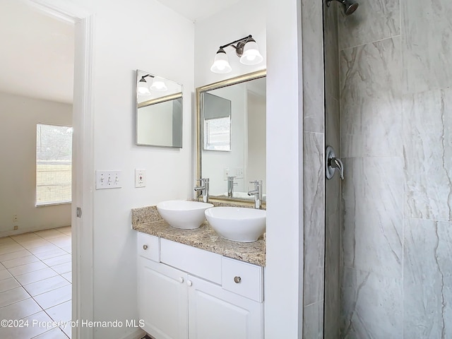 bathroom with tile patterned flooring, vanity, and tiled shower