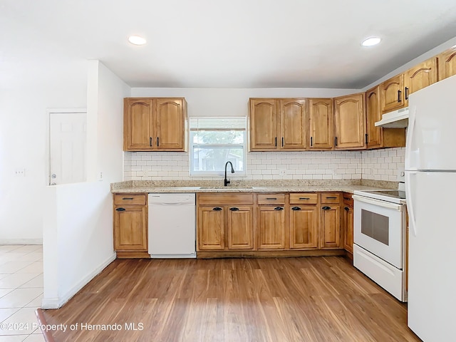 kitchen with decorative backsplash, light wood-type flooring, white appliances, and sink