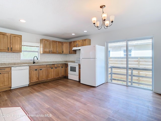 kitchen with decorative backsplash, hardwood / wood-style floors, a chandelier, and white appliances