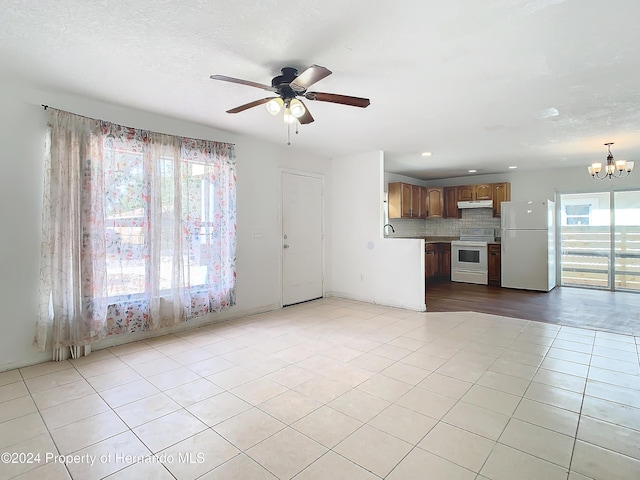 unfurnished living room featuring sink, light tile patterned floors, and ceiling fan with notable chandelier