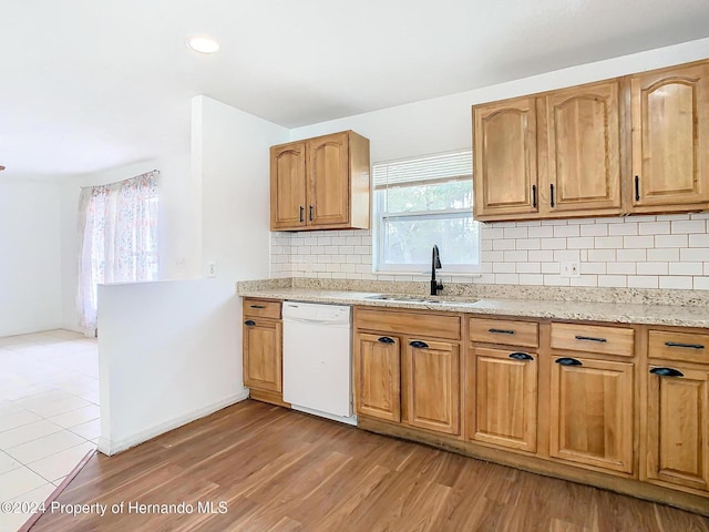 kitchen with dishwasher, sink, light hardwood / wood-style flooring, light stone countertops, and tasteful backsplash