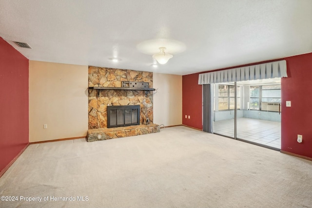 unfurnished living room featuring a stone fireplace, light carpet, and a textured ceiling