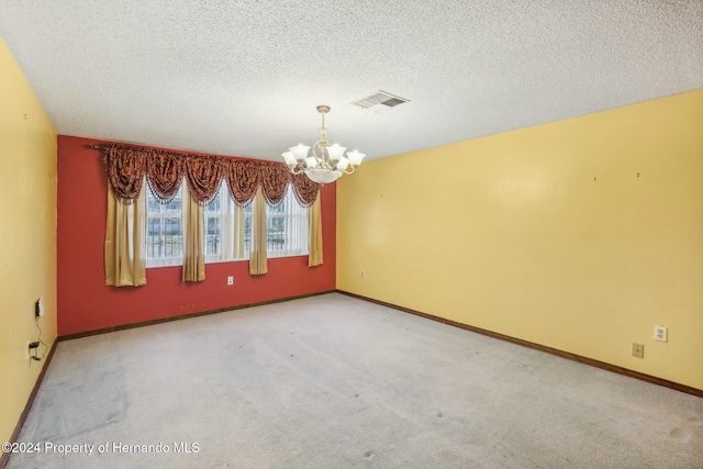 carpeted spare room with a chandelier and a textured ceiling