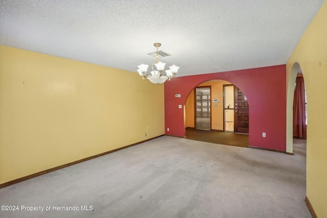 empty room with an inviting chandelier, carpet floors, and a textured ceiling