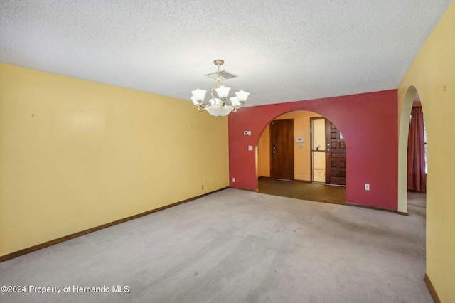 carpeted empty room with a textured ceiling and an inviting chandelier