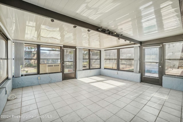 unfurnished sunroom featuring cooling unit and beam ceiling