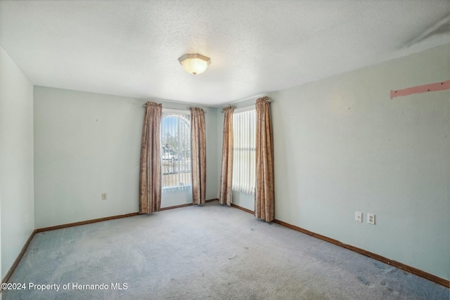 carpeted spare room with a textured ceiling