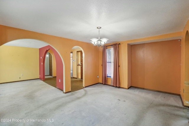 unfurnished room featuring carpet and a chandelier