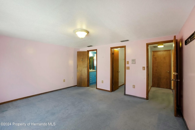 unfurnished bedroom featuring light carpet and ensuite bathroom