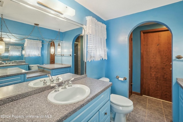 bathroom featuring a shower with door, vanity, tile patterned floors, and toilet