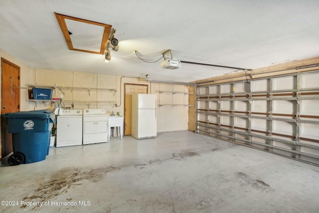 garage featuring a garage door opener, white fridge, and washing machine and clothes dryer