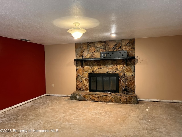 unfurnished living room featuring concrete flooring, a stone fireplace, and a textured ceiling