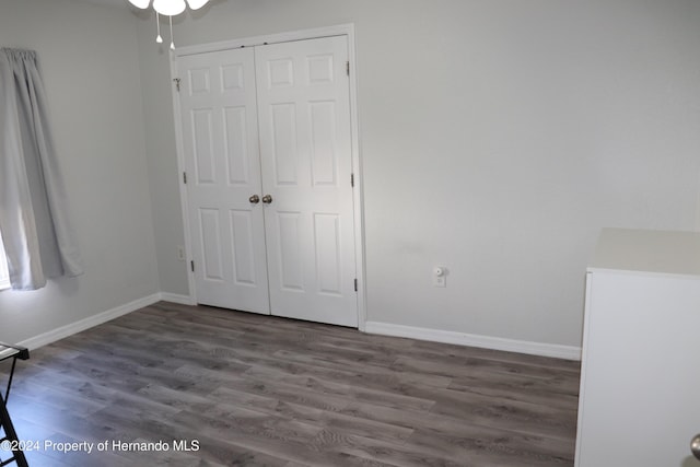 unfurnished bedroom with dark wood-type flooring and a closet