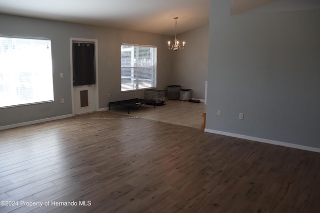 spare room with hardwood / wood-style flooring and an inviting chandelier