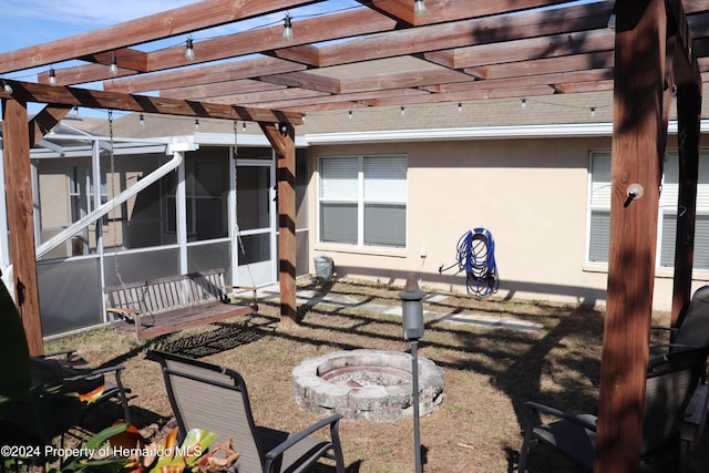 exterior space featuring a pergola, an outdoor fire pit, and a sunroom