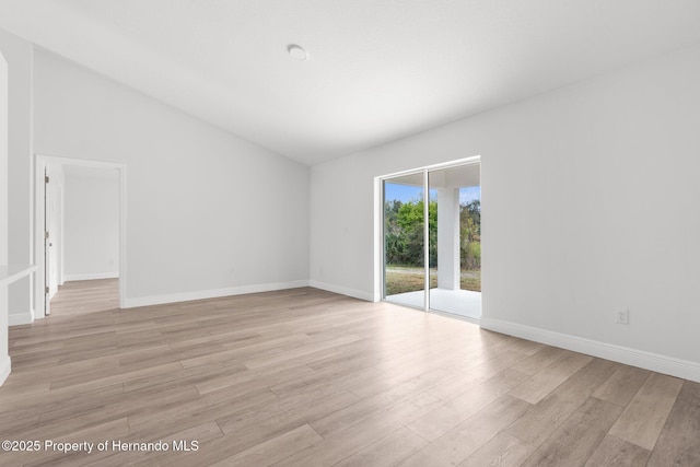 empty room featuring lofted ceiling, light wood-style flooring, and baseboards