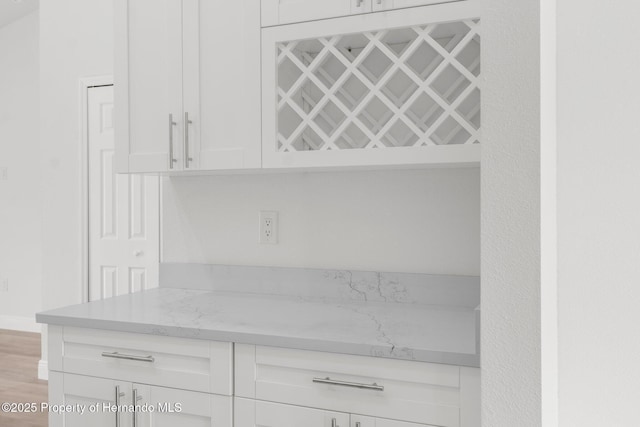 interior space with light stone counters, wood finished floors, and white cabinets