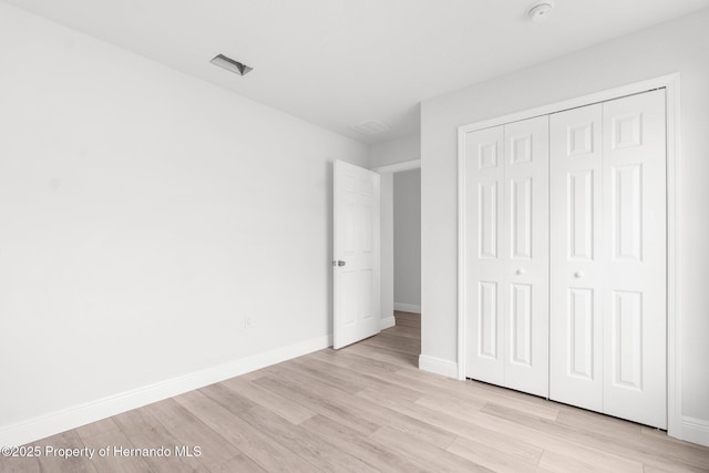 unfurnished bedroom with a closet, light wood-type flooring, and baseboards