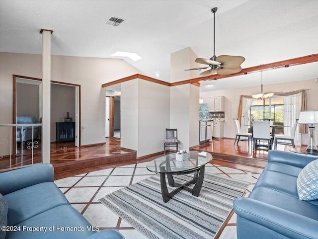 living room with ceiling fan, vaulted ceiling with skylight, and light wood-type flooring