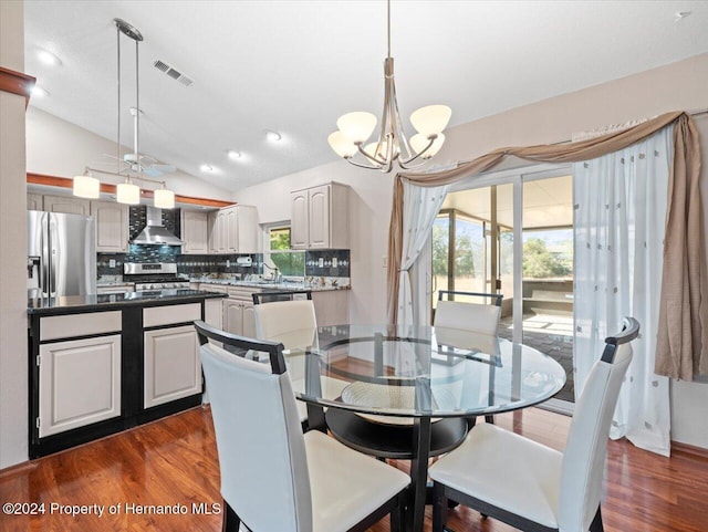 dining room with dark wood-type flooring, a chandelier, lofted ceiling, and sink