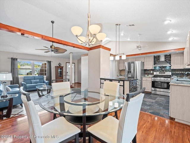 dining area featuring ceiling fan with notable chandelier, dark hardwood / wood-style flooring, vaulted ceiling, and sink