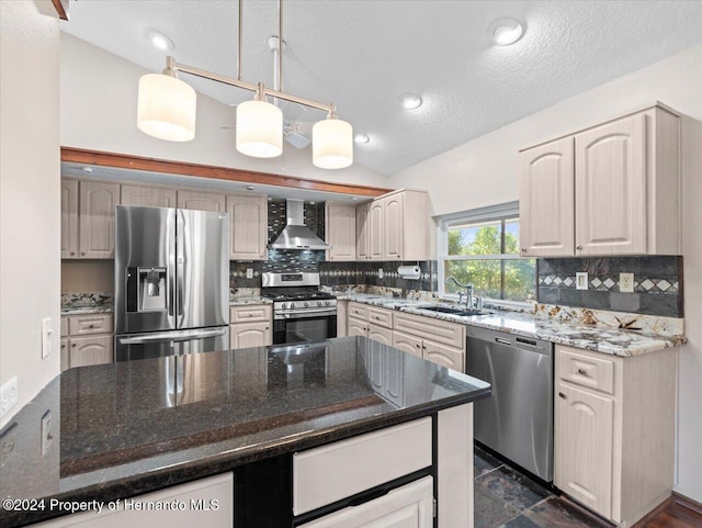 kitchen with sink, wall chimney exhaust hood, a textured ceiling, vaulted ceiling, and appliances with stainless steel finishes