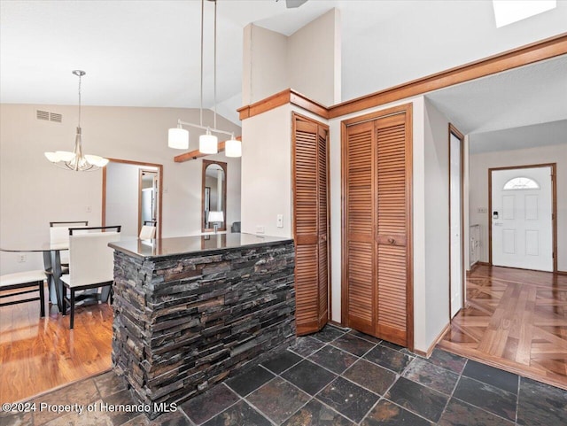 kitchen featuring hanging light fixtures, dark parquet floors, high vaulted ceiling, kitchen peninsula, and a chandelier