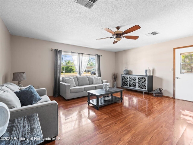 living room featuring ceiling fan, wood-type flooring, and a textured ceiling