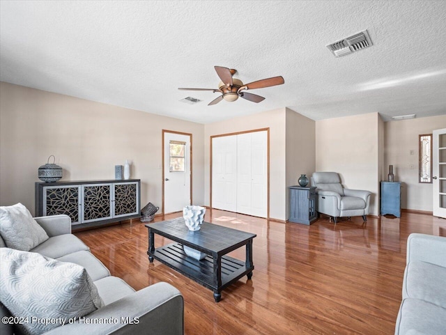 living room with hardwood / wood-style floors, ceiling fan, and a textured ceiling